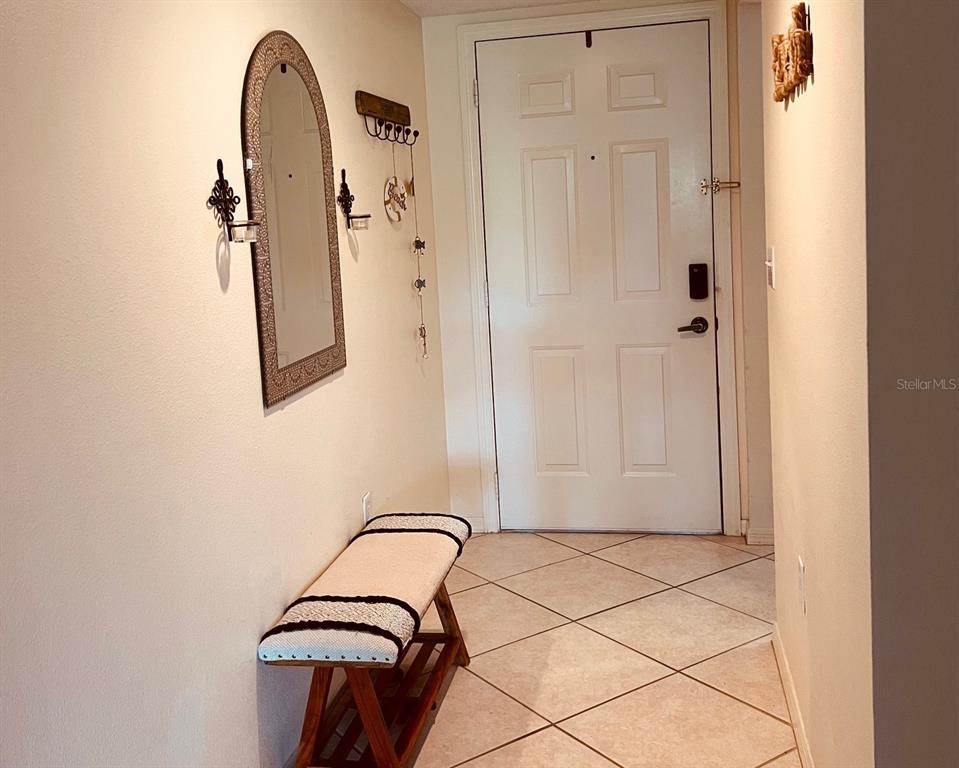An entryway features a white door, a wooden bench with a cushion, and a wall mirror — 9330 CLUBSIDE CIRCLE UNIT 3209, SARASOTA, FL