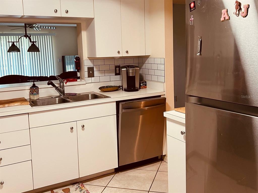 A kitchen features white cabinets, stainless steel appliances, a subway tile backsplash, and a sink — 9330 CLUBSIDE CIRCLE UNIT 3209, SARASOTA, FL