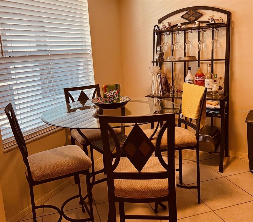 A dining area features a glass-topped table with four chairs and a metal baker's rack — 9330 CLUBSIDE CIRCLE UNIT 3209, SARASOTA, FL