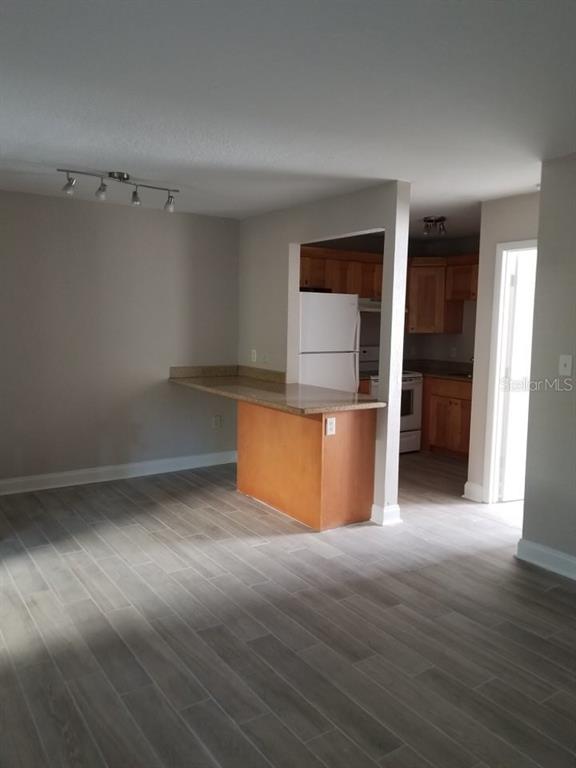 A kitchen with wood cabinets and a breakfast bar overlooks a room with gray flooring — 3914 W NEPTUNE STREET UNIT 11, TAMPA, FL