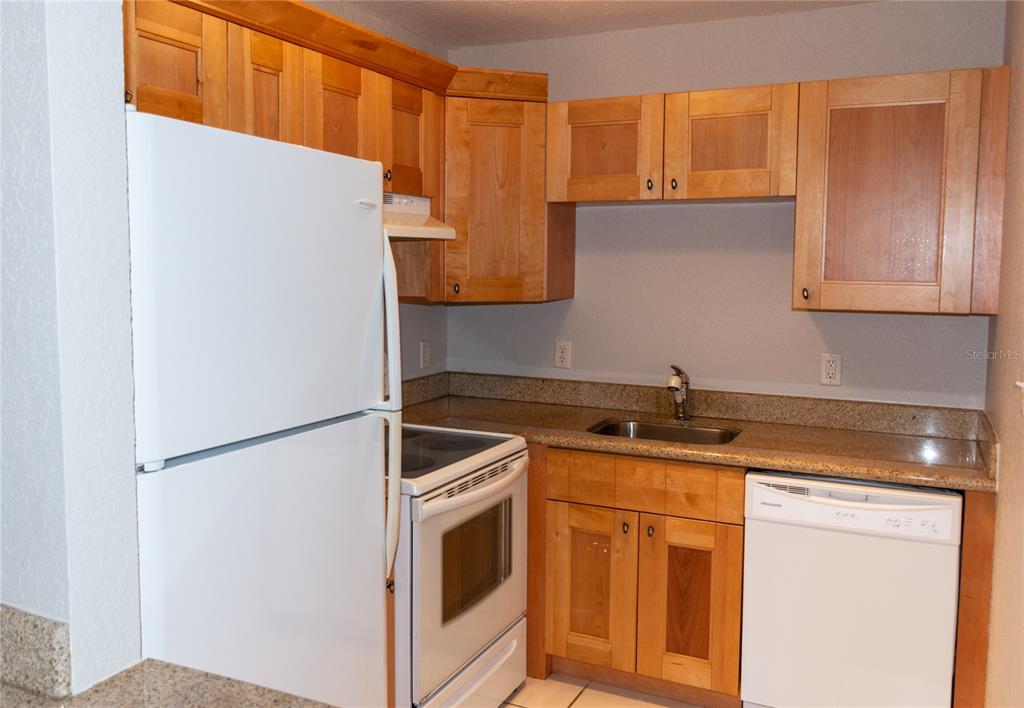A kitchen features light wood cabinets, white appliances, and speckled granite countertops — 3914 W NEPTUNE STREET UNIT 11, TAMPA, FL
