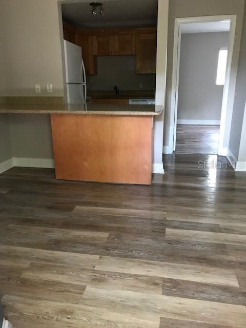 A kitchen with wood cabinets and a breakfast bar overlooks a room with wood-look flooring — 3914 W NEPTUNE STREET UNIT 11, TAMPA, FL