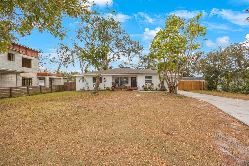 A single-story white house with a hip roof sits behind a large, dry grassy yard — 2504 W FLETCHER AVENUE, TAMPA, FL