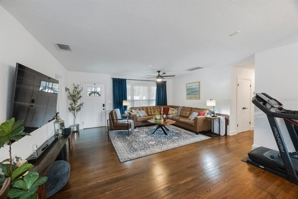 A living room features hardwood floors, a brown sectional sofa, and a treadmill — 2504 W FLETCHER AVENUE, TAMPA, FL