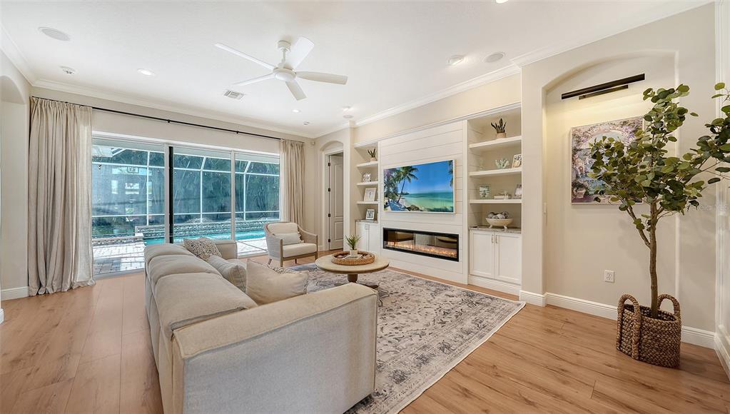 A living room features a fireplace, built-in shelving, a large sofa, and sliding glass doors — 3921 MARAVIC PLACE, SARASOTA, FL