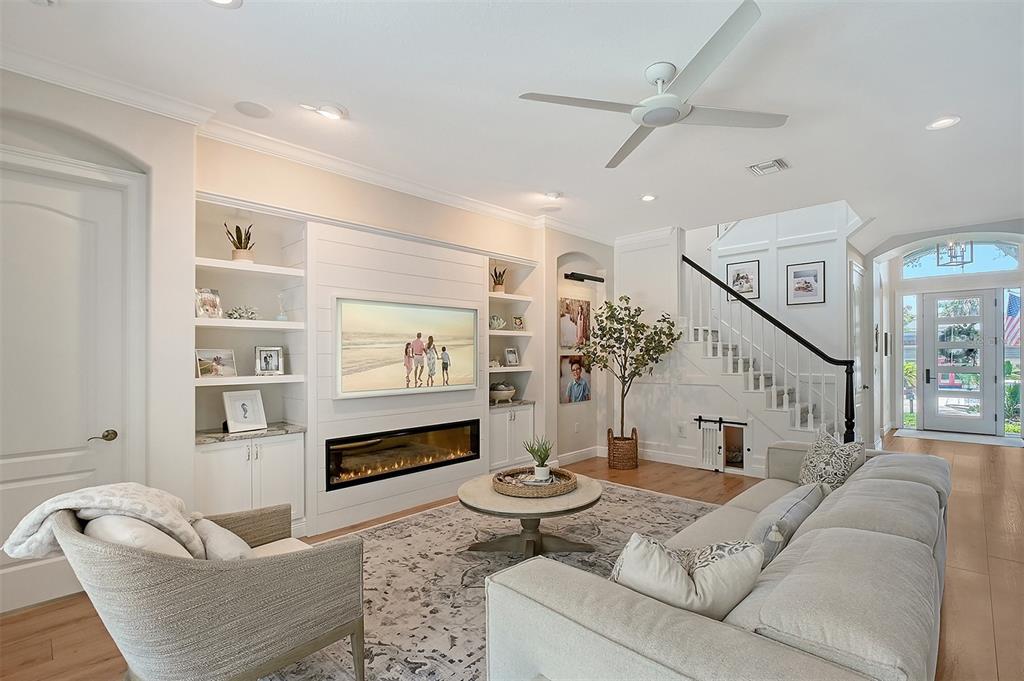 A bright living room features a white shiplap fireplace wall, built-in shelving, and a staircase — 3921 MARAVIC PLACE, SARASOTA, FL