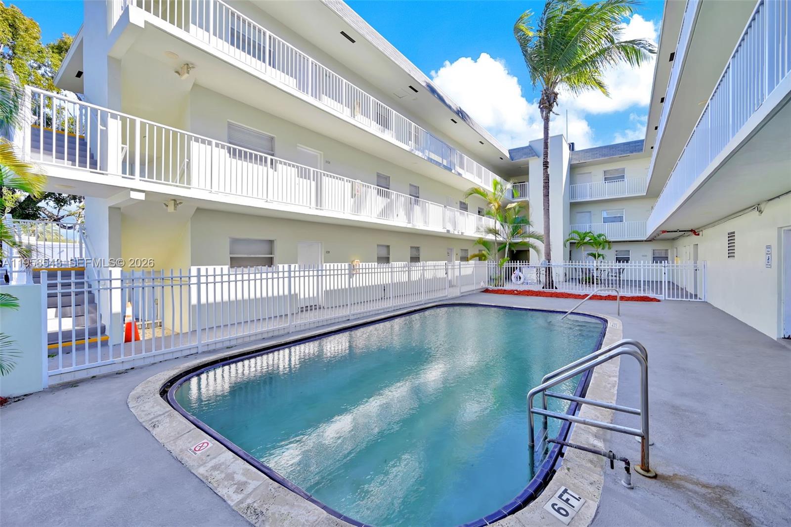 An outdoor swimming pool is situated in the courtyard of a multi-story apartment building — 12890 NE 8th Ave # 208, North Miami FL 33161, NORTH MIAMI, FL
