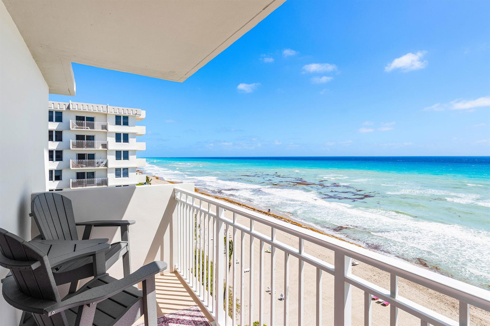 A balcony with two gray chairs overlooks a sandy beach and the turquoise ocean — 3301 S Ocean Boulevard # 810, Highland Beach FL 33487, HIGHLAND BEACH, FL