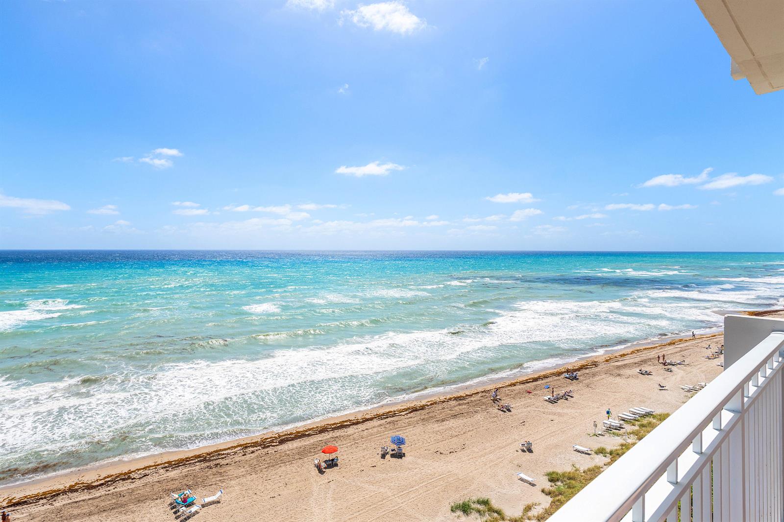 A high-angle view of a sandy beach and ocean from a white balcony — 3301 S Ocean Boulevard # 810, Highland Beach FL 33487, HIGHLAND BEACH, FL