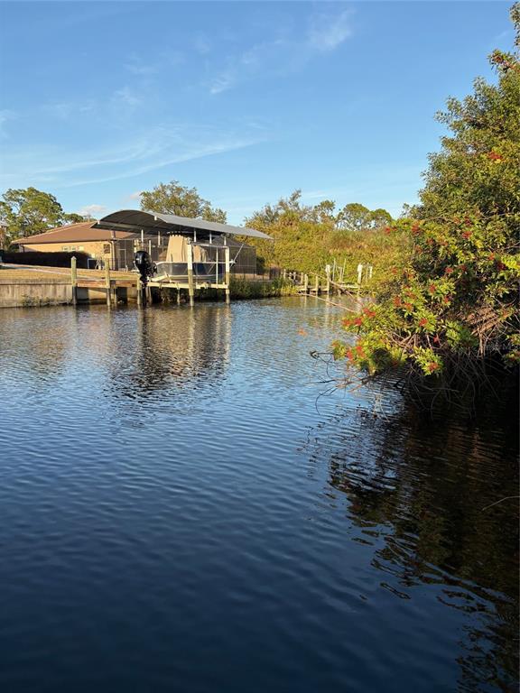 A boat under a covered lift sits on a canal next to a residential backyard — 13333 PALAU CIRCLE, PORT CHARLOTTE, FL