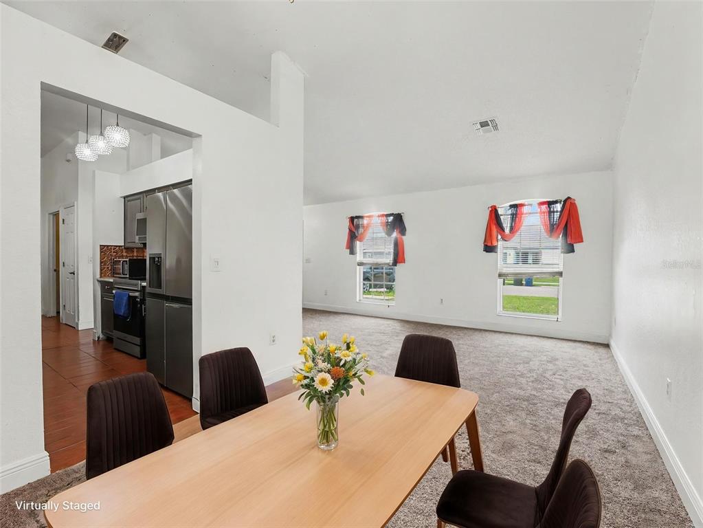 A dining area with a wooden table and chairs overlooks a carpeted living room — 1335 LAUREL GLEN DR, BARTOW, FL
