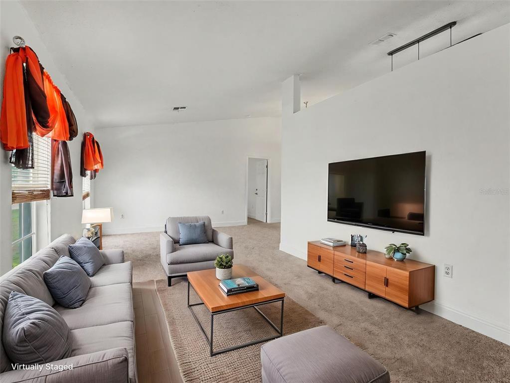 A living room features a gray sofa, armchair, wooden coffee table, and wall-mounted television — 1335 LAUREL GLEN DR, BARTOW, FL