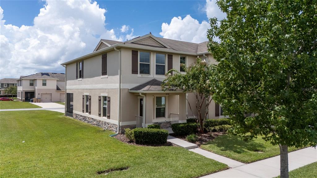 A two-story tan stucco house with brown shutters, stone accents, and a front porch — 1854 KATZ CROSSING DRIVE, KISSIMMEE, FL