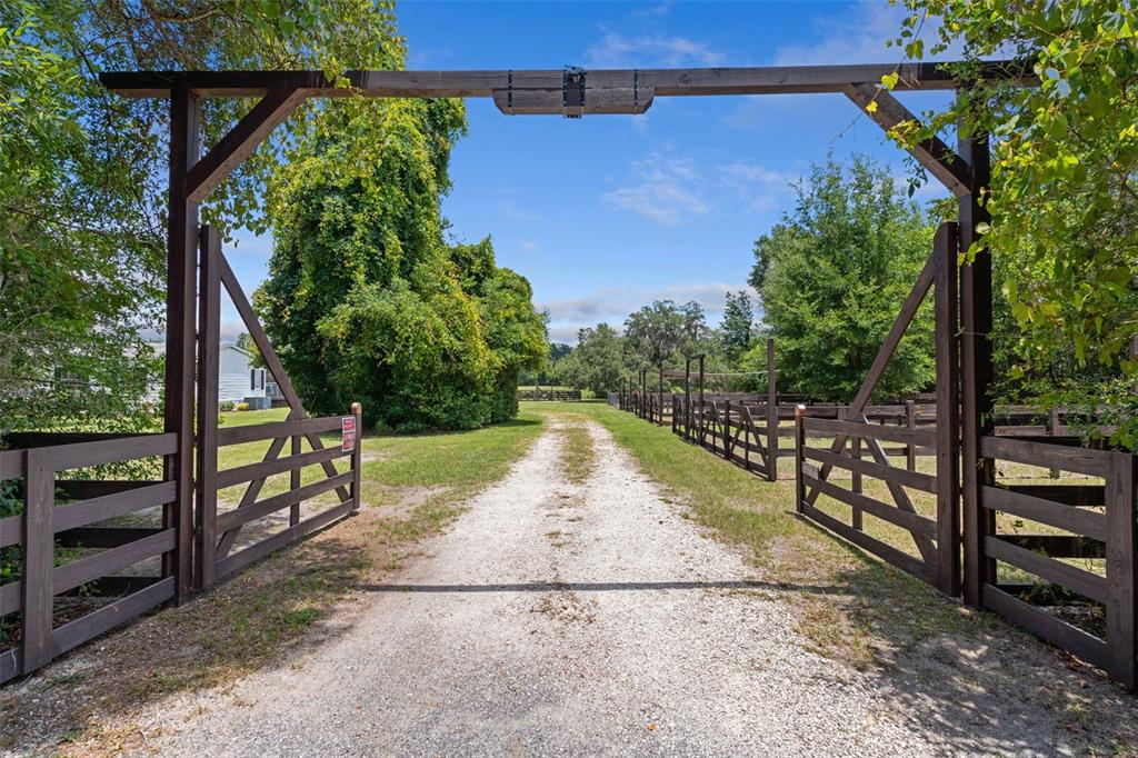 A gravel driveway leads through a wooden gate entrance on a rural property — 26255 LAMBETH ROAD, BROOKSVILLE, FL