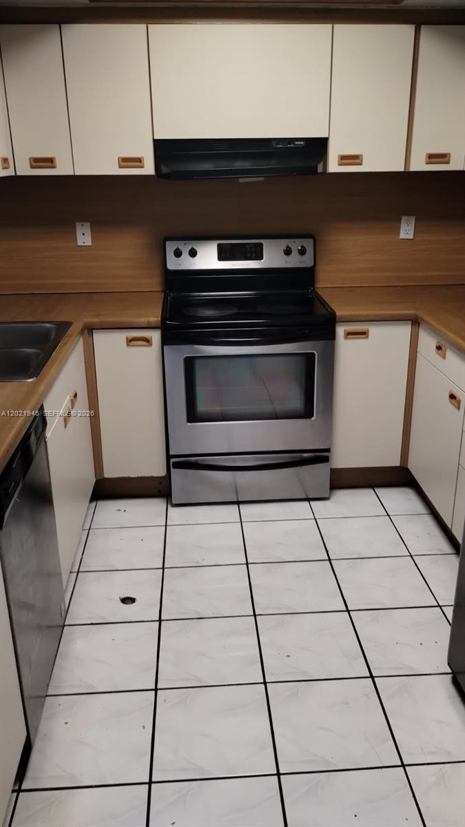 A kitchen features white cabinets, wood-look countertops, a stainless steel stove, and white tiled floors — 12455 SW 93rd Ter # 208T, Miami FL 33186, MIAMI, FL