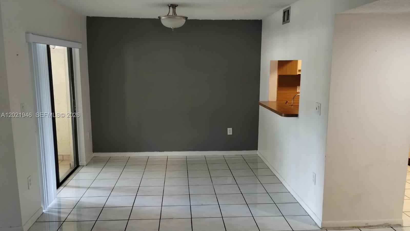 This dining area features white tile flooring, a dark gray accent wall, and a pass-through window — 12455 SW 93rd Ter # 208T, Miami FL 33186, MIAMI, FL