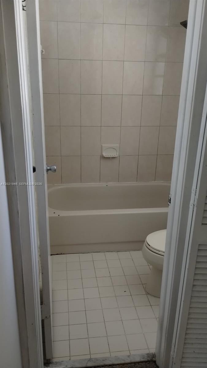 A bathroom features a beige bathtub, white tiled walls, and a white toilet — 12455 SW 93rd Ter # 208T, Miami FL 33186, MIAMI, FL