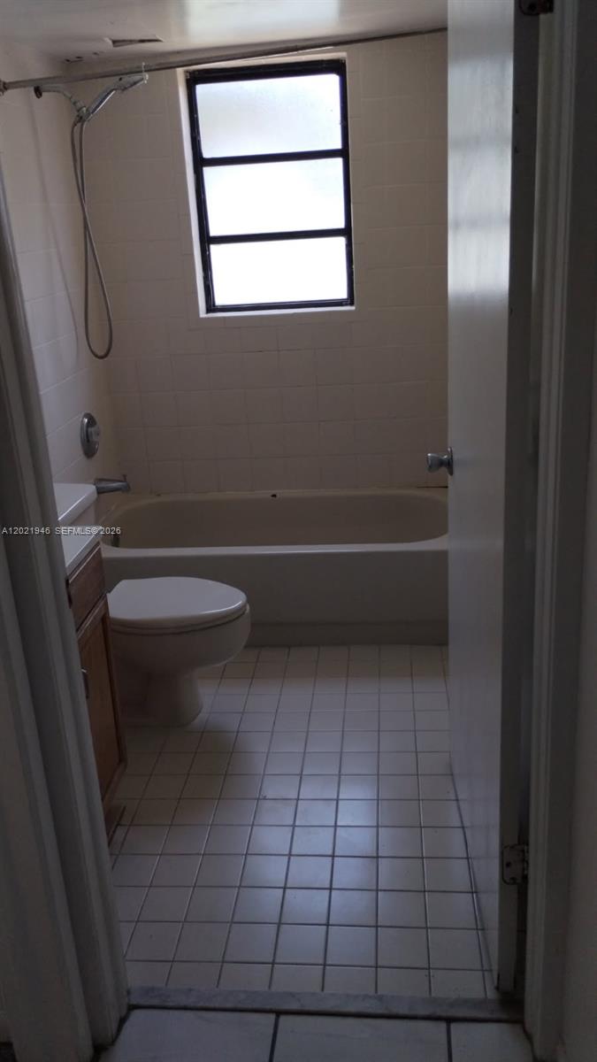 A bathroom features a white tiled floor, a toilet, and a bathtub with a showerhead — 12455 SW 93rd Ter # 208T, Miami FL 33186, MIAMI, FL