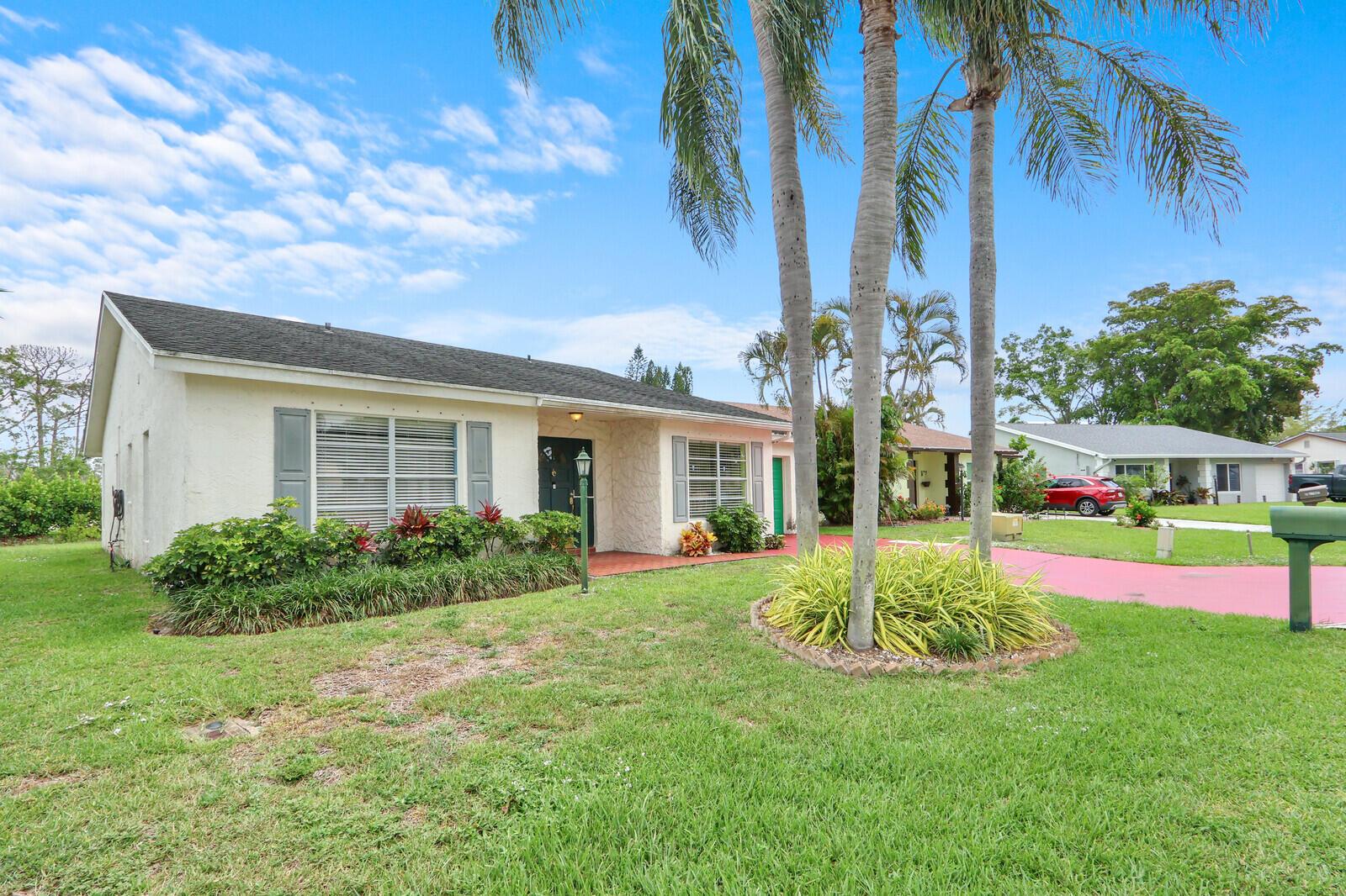 A single-story house with a white exterior, a dark roof, and palm trees in front — 7156 Pine Bluff Drive, Lake Worth FL 33467, LAKE WORTH, FL