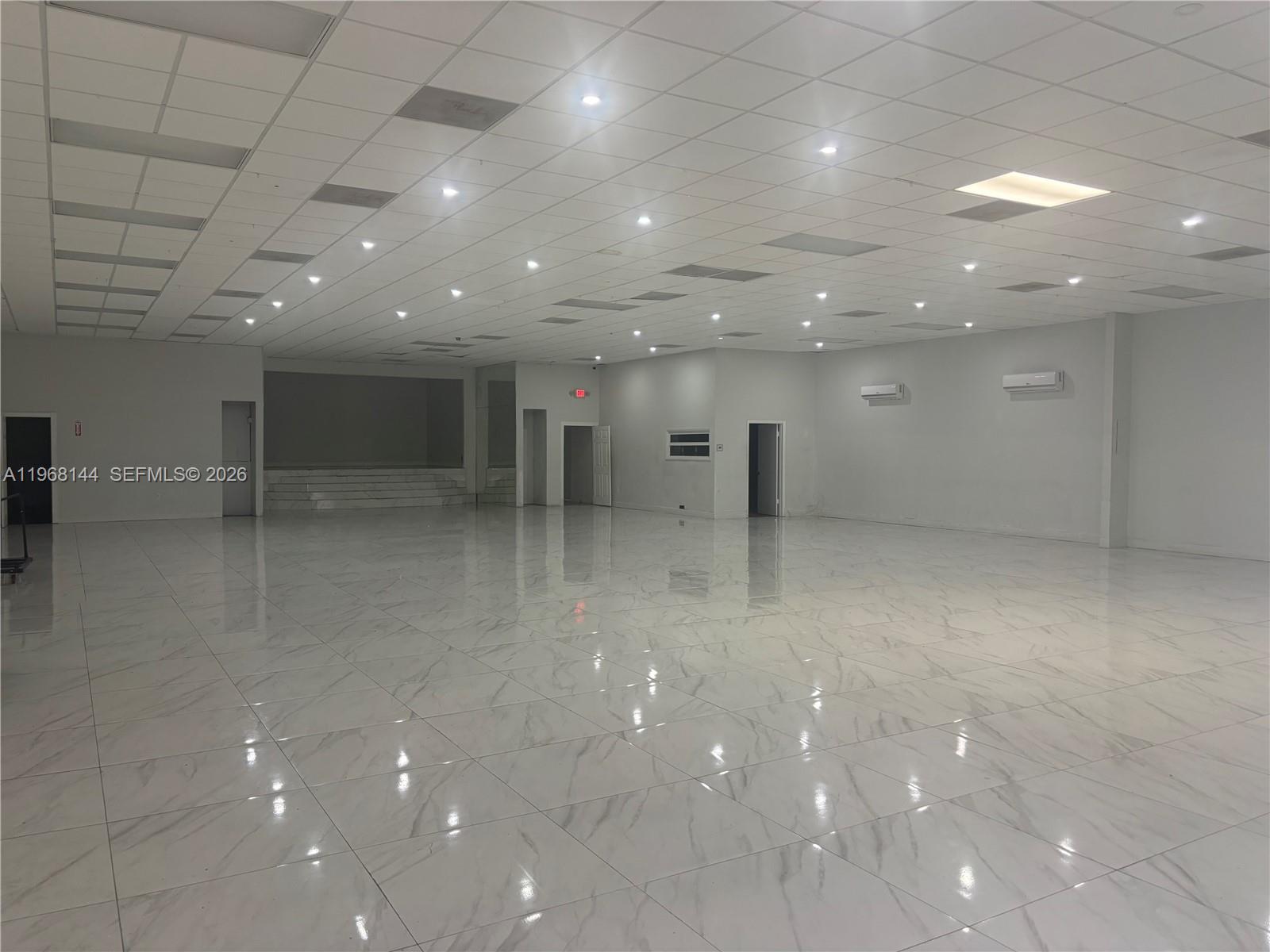 A large, empty commercial space features white marble-look tile flooring and a drop ceiling — 4658 Palm Ave, Hialeah FL 33012, HIALEAH, FL