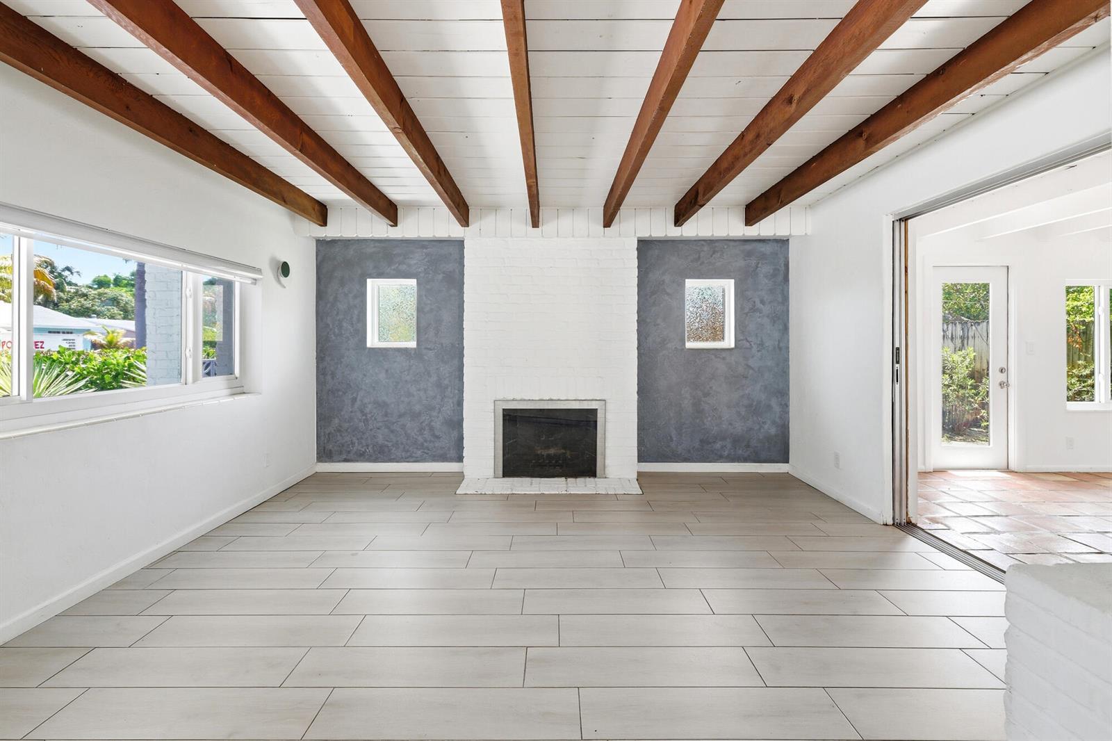 A living room features a white brick fireplace, gray accent walls, and exposed wood beams — 1225 15th Avenue N, FL 33460, FL