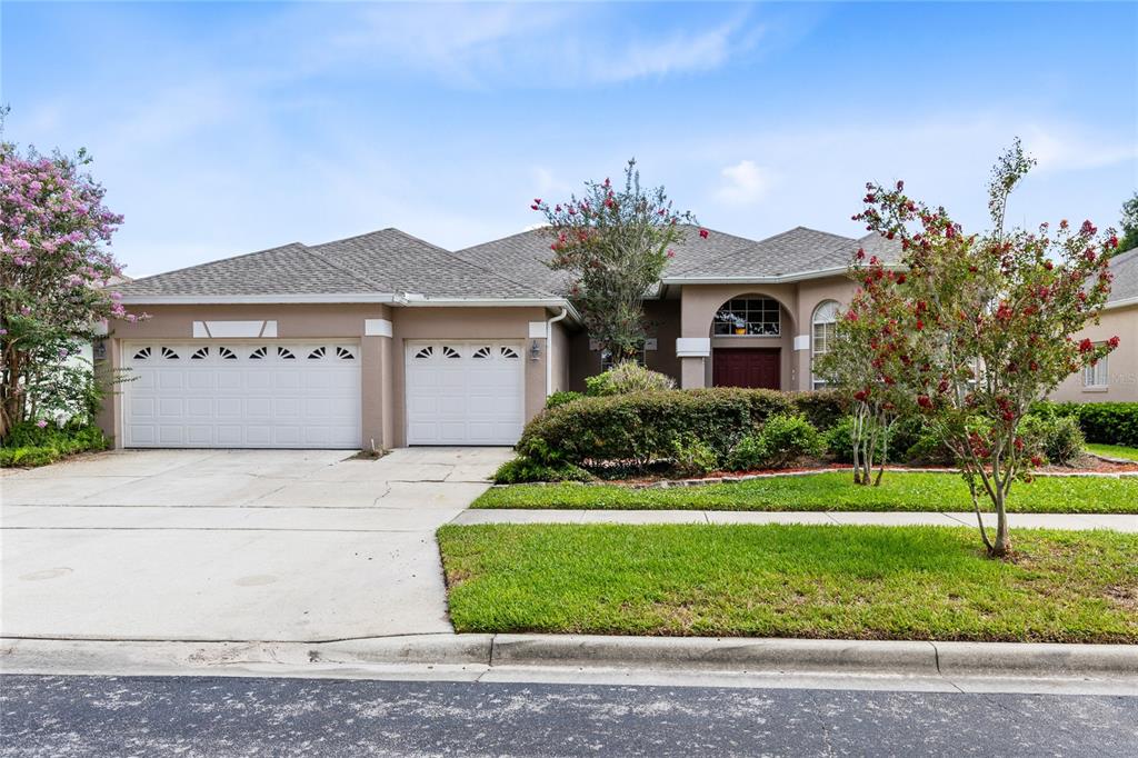 A single-story house with a two-car garage, tan stucco exterior, and a landscaped front yard — 3670 HALF MOON DRIVE, ORLANDO, FL