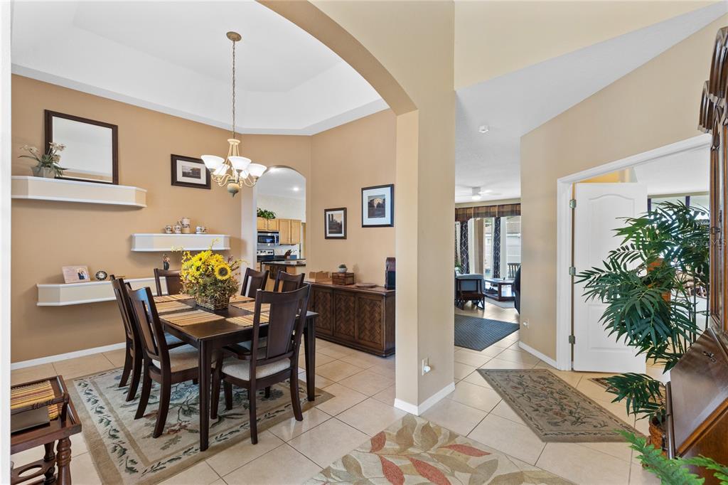 A dining room with a tray ceiling, tile floors, and an adjacent view of the kitchen — 3670 HALF MOON DRIVE, ORLANDO, FL