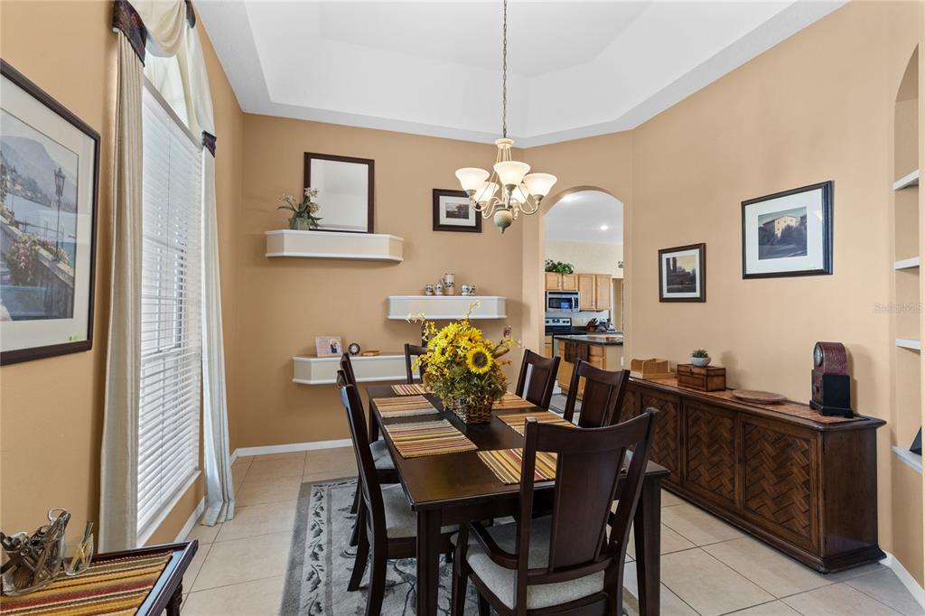 A dining room with a dark wood table, chairs, and a matching sideboard on tile flooring — 3670 HALF MOON DRIVE, ORLANDO, FL
