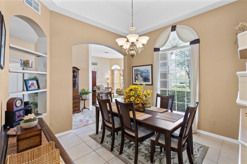 A dining room with a wooden table, chairs, a chandelier, and an arched entryway — 3670 HALF MOON DRIVE, ORLANDO, FL