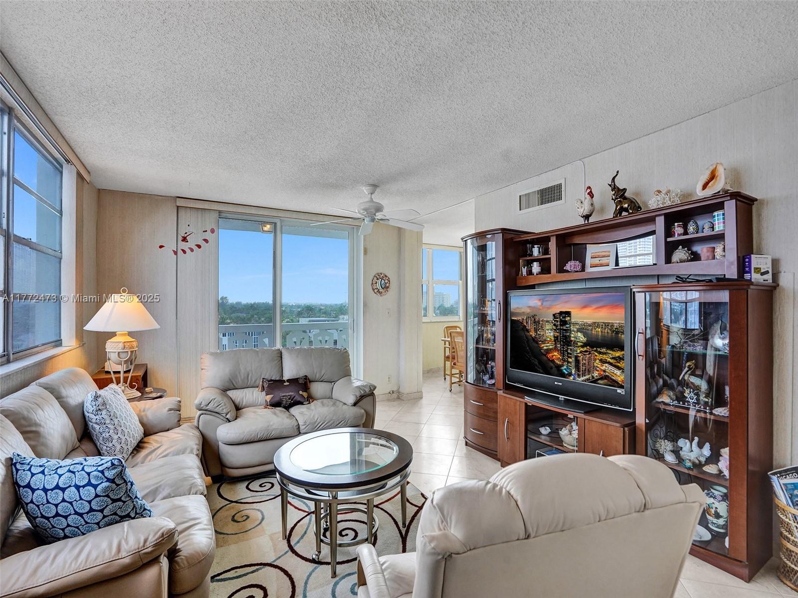 A living room features beige leather furniture, a glass coffee table, and a large wooden entertainment center — 3113 S Ocean Dr # 710, Hallandale Beach FL 33009, HALLANDALE BEACH, FL