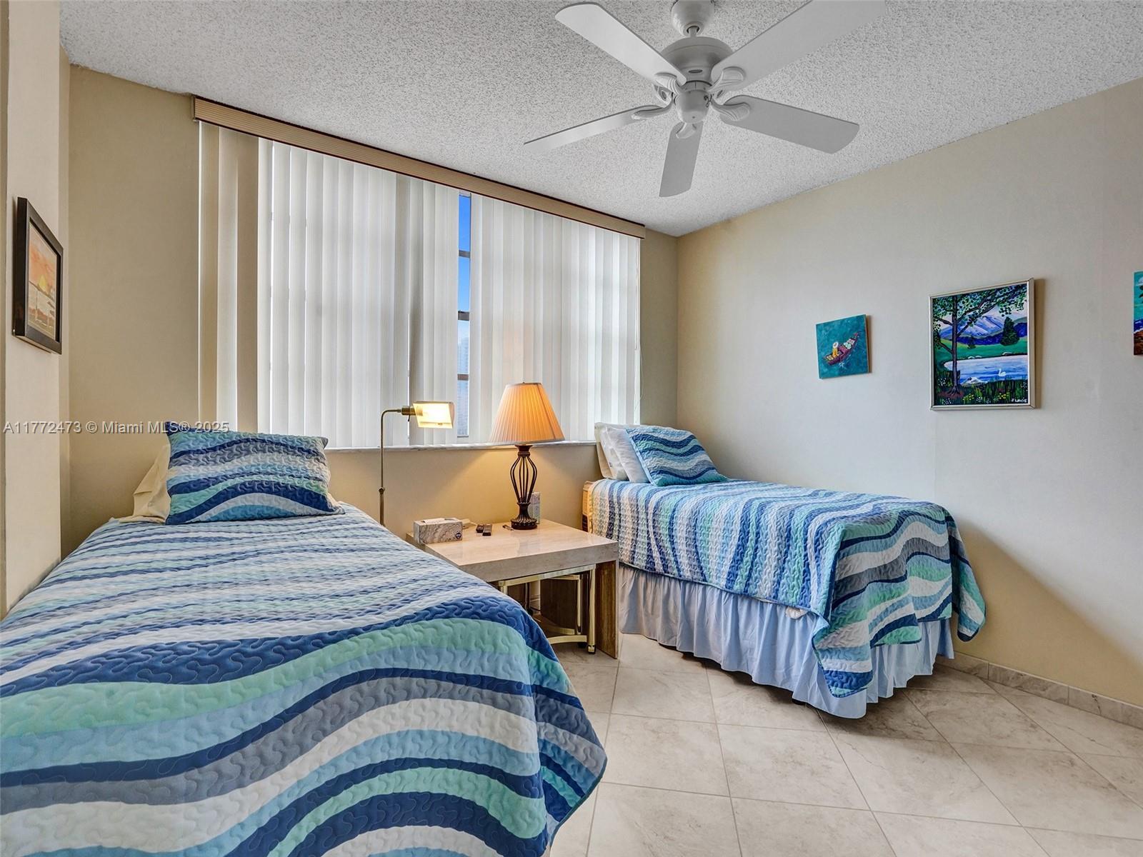A bedroom features two twin beds, a nightstand with a lamp, and a ceiling fan — 3113 S Ocean Dr # 710, Hallandale Beach FL 33009, HALLANDALE BEACH, FL