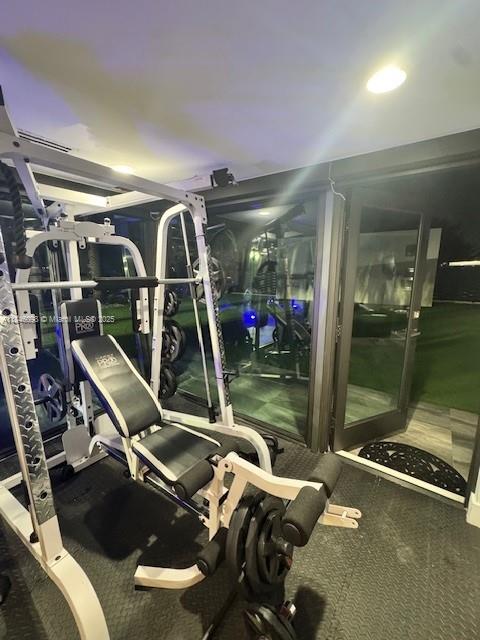 A home gym features a white multi-station weight machine on a black rubber floor — 4229 W 7th Ln, Hialeah FL 33012, HIALEAH, FL