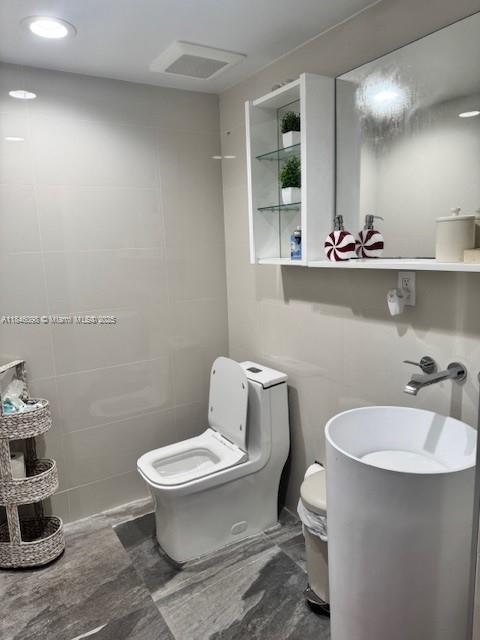 A modern bathroom features a white pedestal sink, a toilet, and wall-mounted shelving — 4229 W 7th Ln, Hialeah FL 33012, HIALEAH, FL