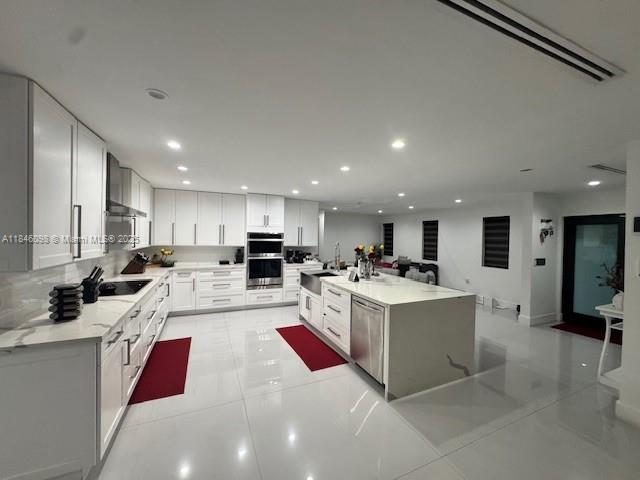 A modern white kitchen features a large center island, stainless steel appliances, and glossy tile flooring — 4229 W 7th Ln, Hialeah FL 33012, HIALEAH, FL