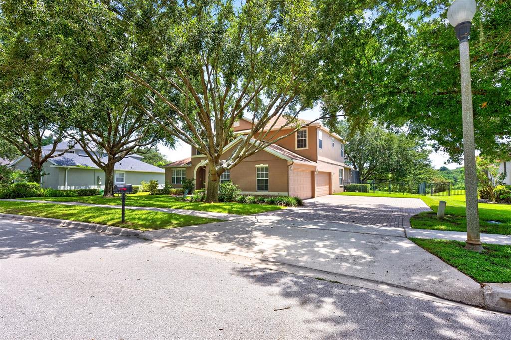 A two-story tan house with a brick driveway and mature trees in the front yard — 825 PARKSIDE POINTE BOULEVARD, APOPKA, FL