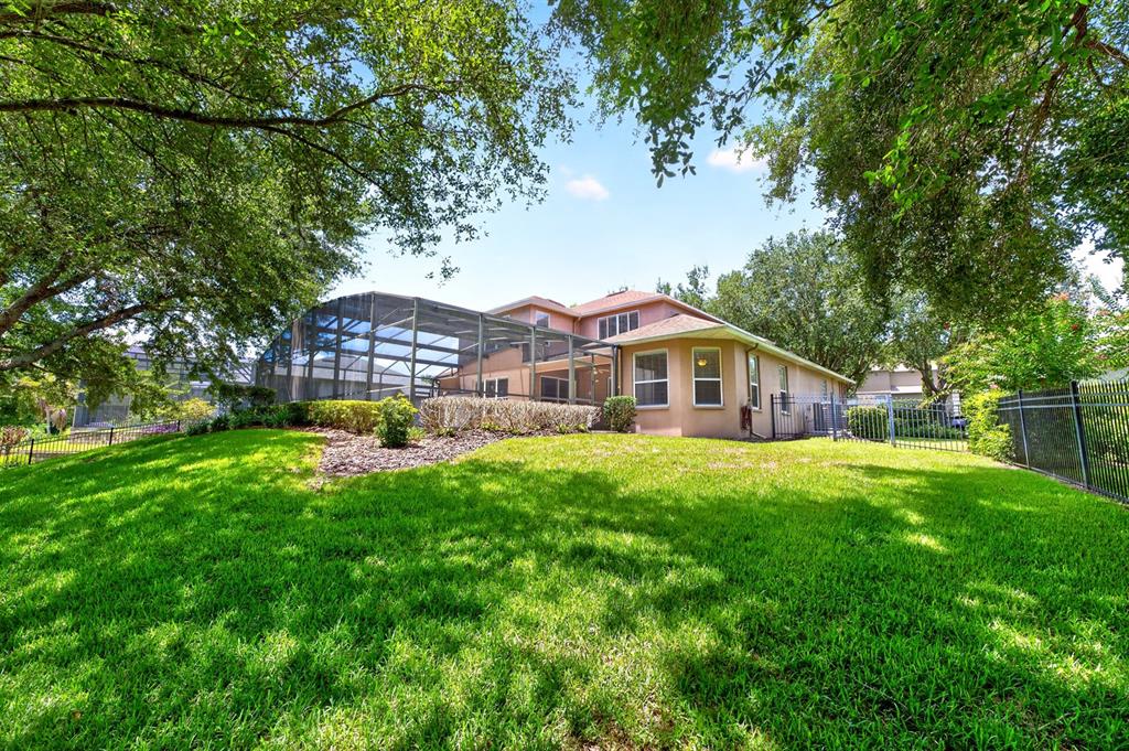 A two-story house with a screened-in pool enclosure sits behind a large, grassy backyard — 825 PARKSIDE POINTE BOULEVARD, APOPKA, FL