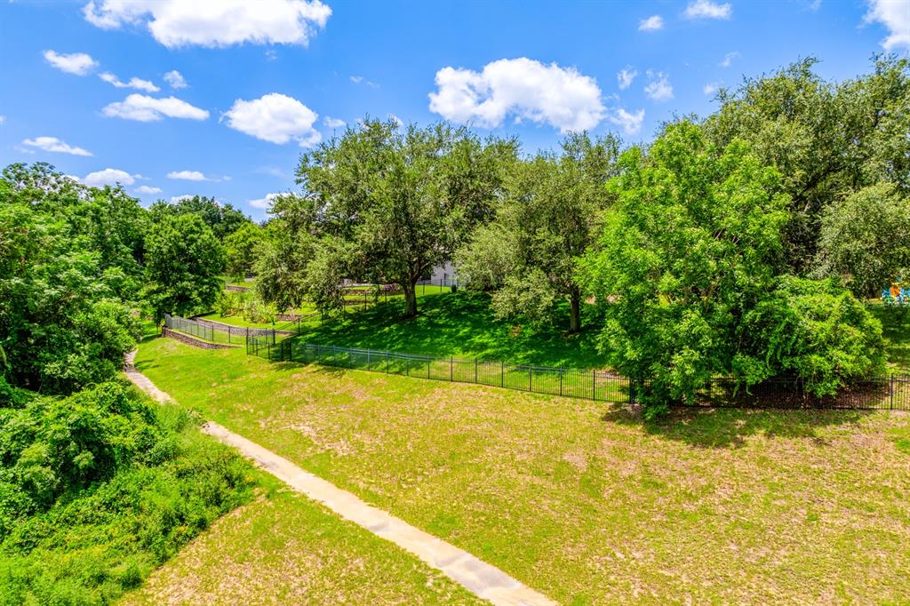 A grassy backyard features a paved path, a black metal fence, and several large trees — 825 PARKSIDE POINTE BOULEVARD, APOPKA, FL
