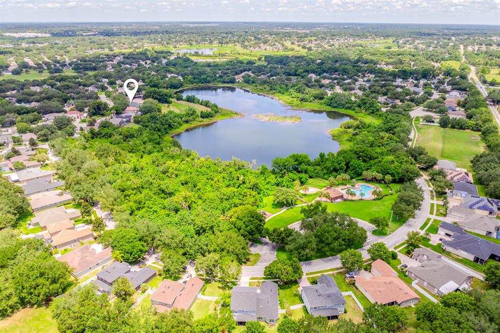 An aerial view shows a residential neighborhood surrounding a lake with a community pool area — 825 PARKSIDE POINTE BOULEVARD, APOPKA, FL