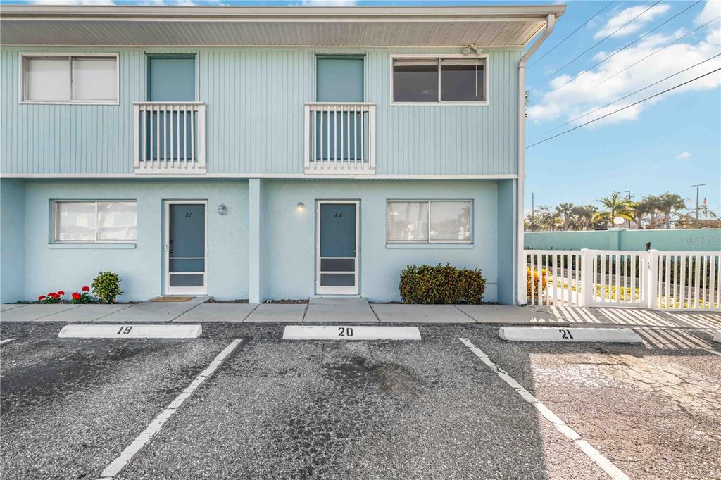 The exterior of a light blue two-story building features numbered parking spaces and unit doors — 3569 BEE RIDGE, SARASOTA, FL