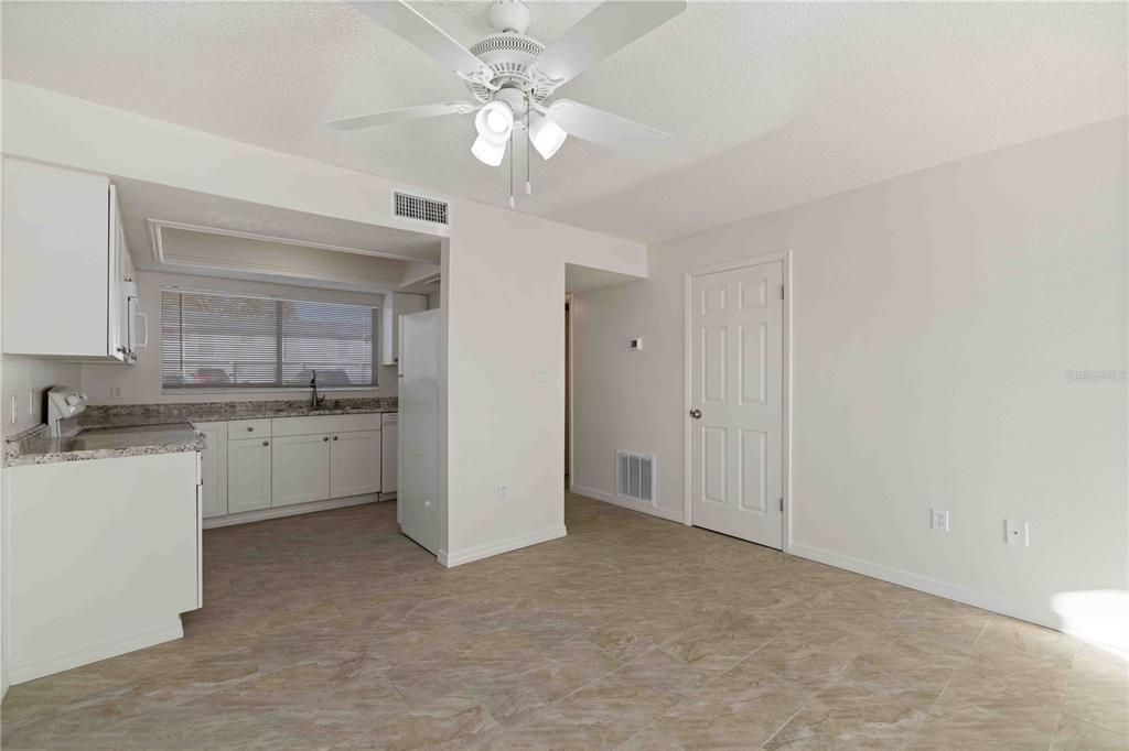 A kitchen with white cabinets and granite countertops opens into a dining area with tile — 3569 BEE RIDGE, SARASOTA, FL