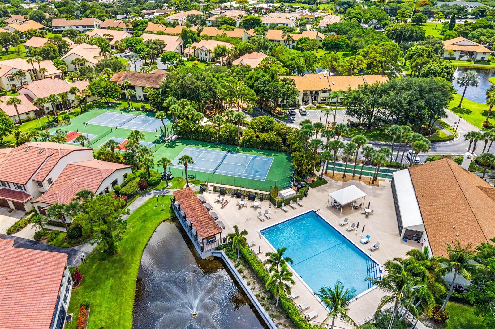 An aerial view shows a swimming pool, tennis courts, and a pond within a residential community — 3315 Lucerne Park Drive, FL 33467, FL