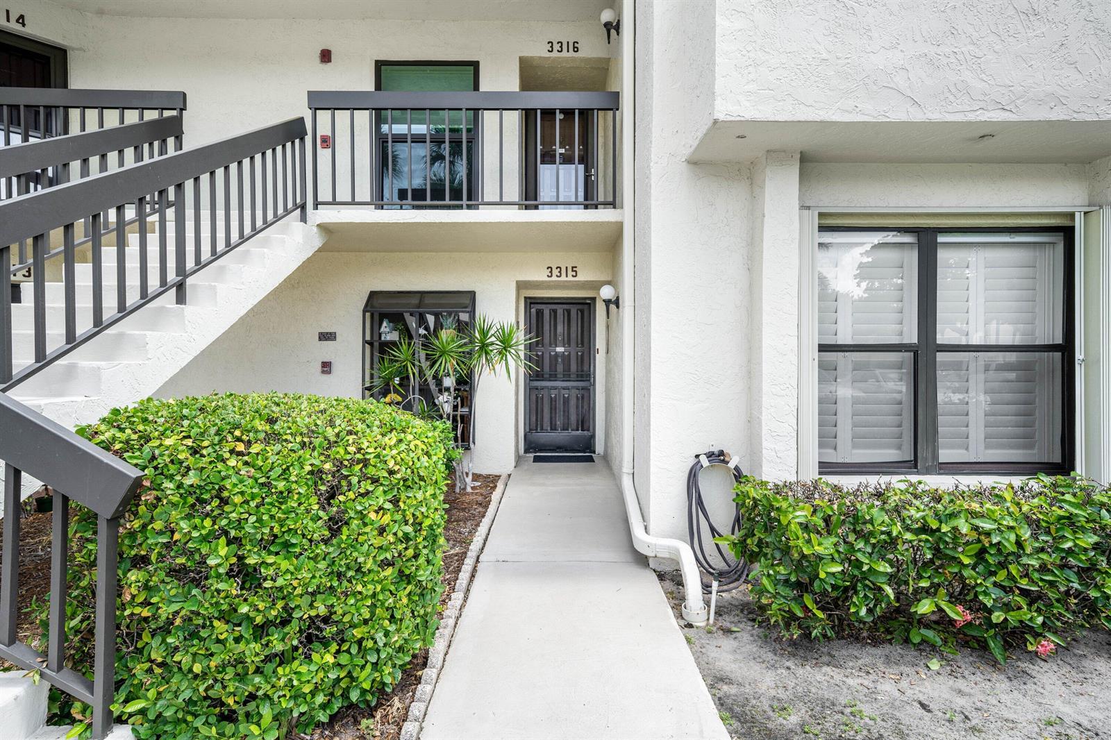 A two-story apartment building exterior features a ground-level entrance, an upper balcony, and stairs — 3315 Lucerne Park Drive, FL 33467, FL