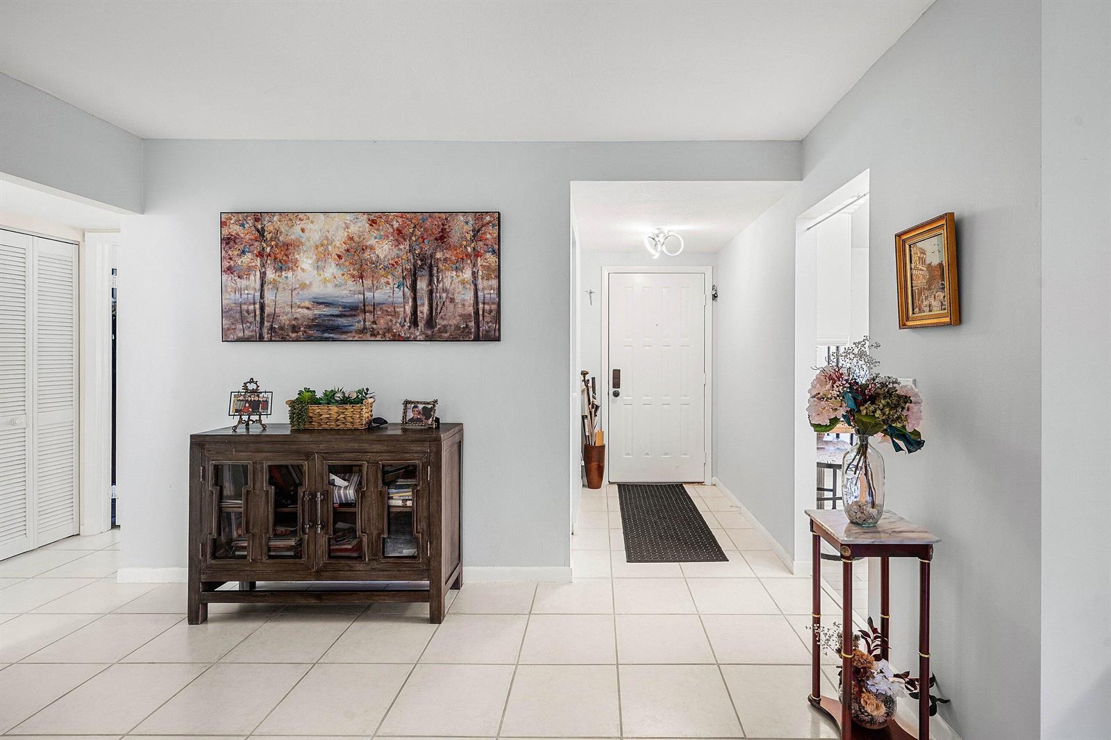 A bright entryway features light tile flooring, a wooden cabinet, and a white front door — 3315 Lucerne Park Drive, FL 33467, FL