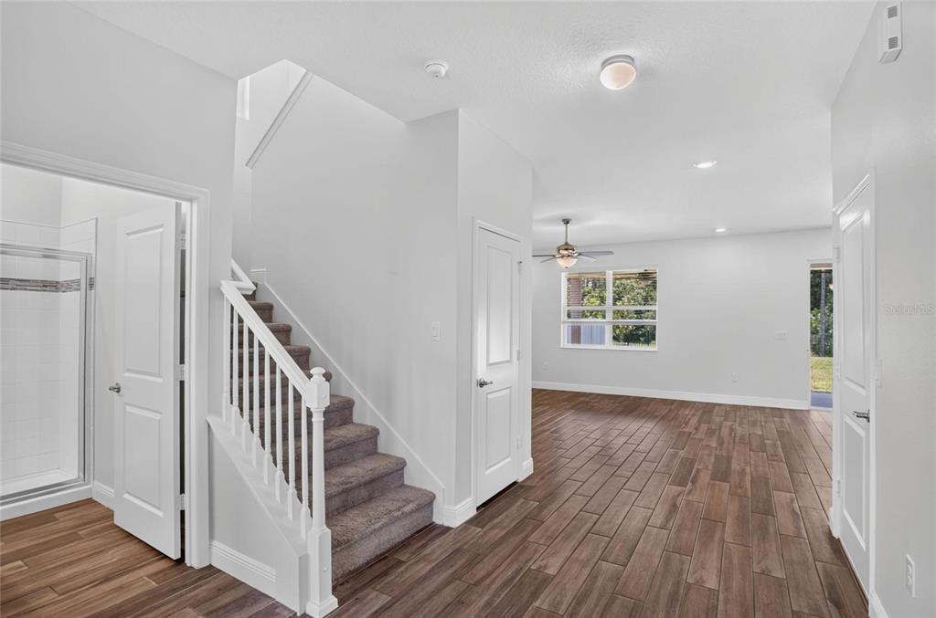 An interior view shows a carpeted staircase, wood-look tile flooring, and an open living area — 16420 WINDING PRESERVE CIRCLE, CLERMONT, FL