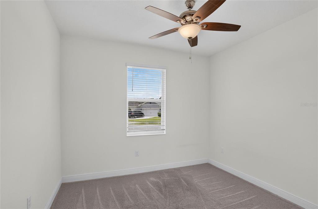 An empty bedroom with light walls, gray carpet, a ceiling fan, and a single window — 16420 WINDING PRESERVE CIRCLE, CLERMONT, FL
