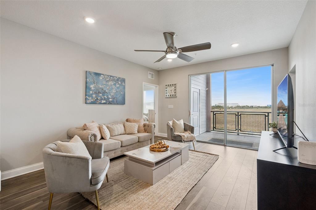 A modern kitchen features white cabinets, stainless steel appliances, and wood-look flooring — 7521 LAUREATE BOULEVARD UNIT 5306, ORLANDO, FL