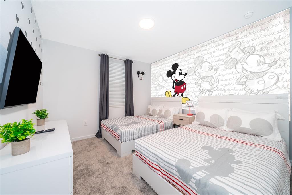 A bedroom features two beds with Mickey Mouse-themed bedding and a large Mickey Mouse wall mural — 8899 CABOT CLIFFS DRIVE UNIT 102, DAVENPORT, FL
