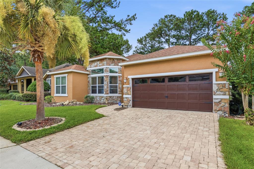 A single-story house with a stone-accented facade, a brown garage door, and a paved driveway — 14504 NW 25TH AVENUE, NEWBERRY, FL