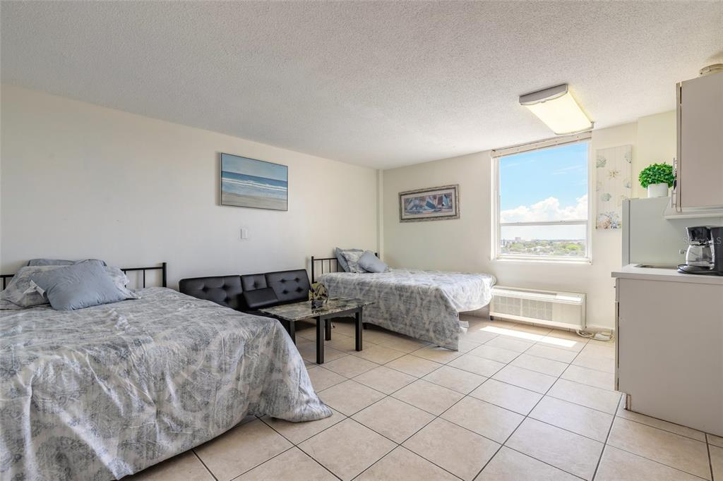 A studio apartment features two beds, a small sofa, tile flooring, and a kitchenette — 701 S ATLANTIC AVENUE UNIT 621, DAYTONA BEACH, FL