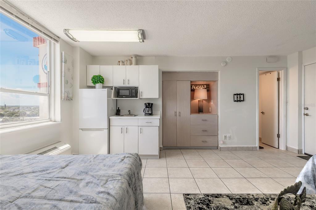A studio apartment features a kitchenette with white cabinets, a refrigerator, and a built-in dresser — 701 S ATLANTIC AVENUE UNIT 621, DAYTONA BEACH, FL
